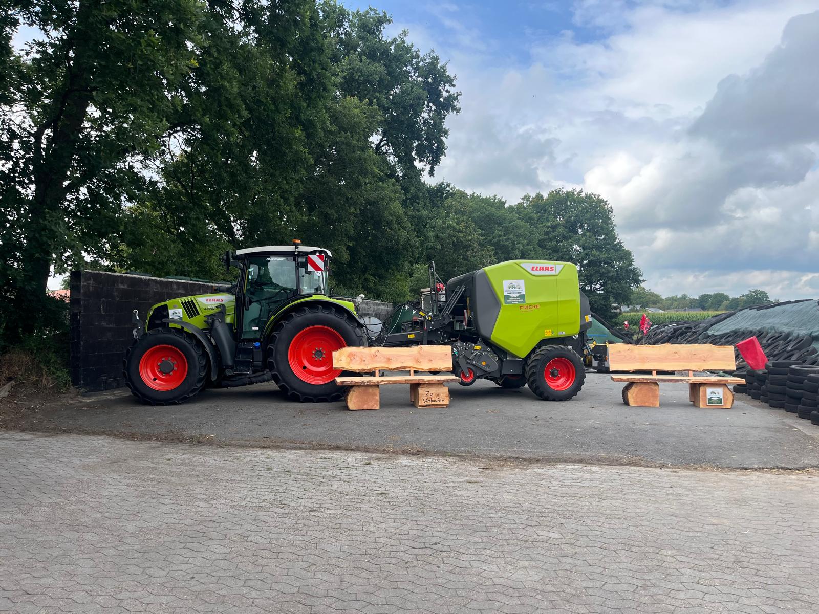 Hof mit CLAAS Traktor, Rundballenpresse und selbstgebauten Holzbänken